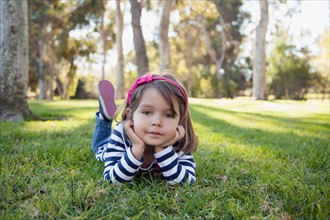 Portrait of girl (4-5 years) lying on grass in park