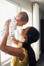 Woman holding up her baby son (2-5 months)