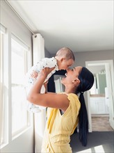 Woman holding up her baby son (2-5 months)