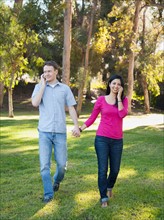 Couple walking and using mobile phone in park