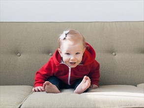 Portrait of baby girl (12-17 months) sitting on sofa