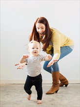 Baby girl (12-17 months) walking while mother assisting her