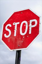 Low angle view of stop sign with bullet holes