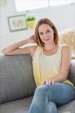 Portrait of young woman relaxing on sofa.