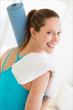 Woman carrying exercise mat and towel.