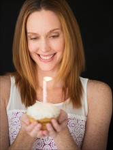Woman holding birthday cupcake.