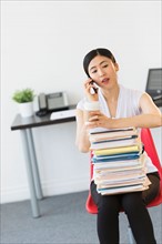 Businesswoman with stack of files talking on phone.
