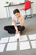 Businesswoman organizing paperwork on floor.