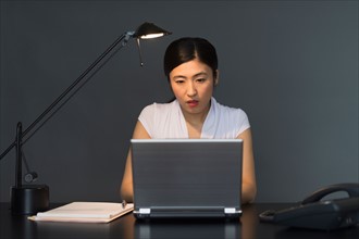 Businesswoman working on laptop at night.