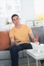 Man eating take out meal and watching television.