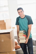 Man packing books into cardboard box at home.
