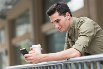 Man drinking coffee and text messaging.