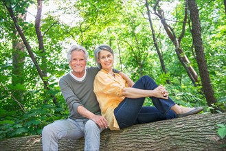 Central Park, New York City. Senior couple sitting on log in forest.