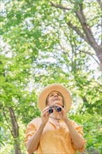 Central Park, New York City. Senior woman with binoculars in park.