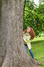 Woman leaning on tree in park.