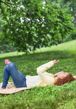 Woman lying on grass in park and using mobile phone.