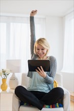 Young woman with digital tablet gesturing in success