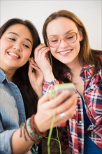 Portrait of two young women listening to music on MP3 player