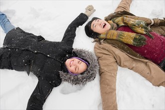Two young people making snow angels