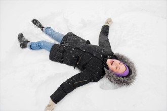 Young woman making snow angel