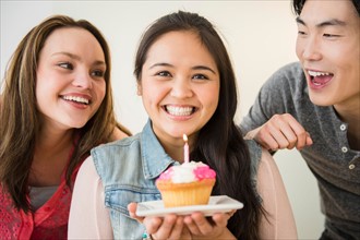 Portrait of happy man and women, one holding cup cake