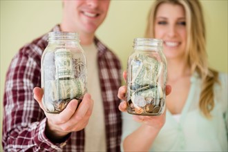 Studio shot of couple holding jars with money