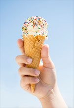 Girl (8-9) holding ice cream against blue sky