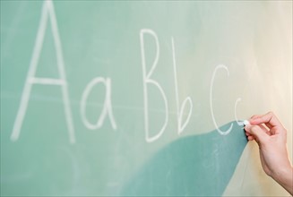 View of letters on blackboard and girl's hand