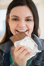 Young woman eating bar of chocolate