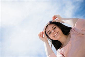 Portrait of young woman standing against cloudy sky