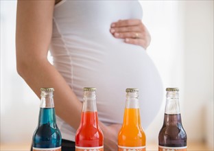 Mid section of pregnant woman, soda bottles in front