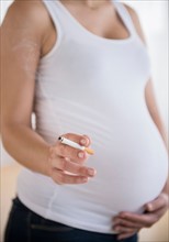 Mid section of pregnant woman holding cigarrete