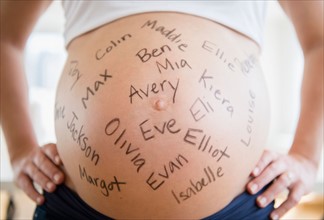 Mid section of pregnant woman with names written on her belly