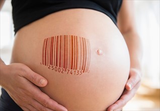 Mid section of pregnant woman with bar code on her belly