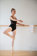 Portrait of teenage (16-17) ballet dancer standing at barre