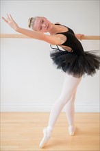 Portrait of teenage (16-17) ballet dancer practicing at barre