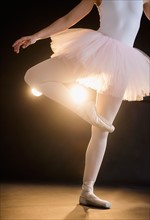 Teenage (16-17) ballerina on stage standing on one leg