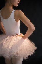 Teenage (16-17) ballerina with hand on hip wearing tutu