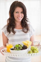 Portrait of young woman holding tray with fresh salad