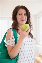 Portrait of young woman holding green apple