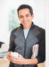 Portrait of man holding newspaper and coffee mug