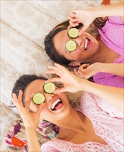 Two women with slices of cucumber on eyes