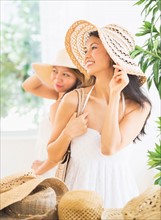 Two women trying on straw hat
