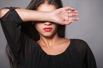 Studio shot of young woman covering her face