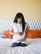 Portrait of pregnant woman sitting on bed