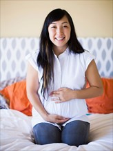 Portrait of pregnant woman sitting on bed
