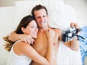 Couple lying on bed photographing themselves