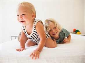 Boy (6-7) and girl (2-3) playing with their baby brother (6-11 months)