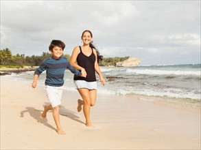 Boy (10-11) running on beach with mother