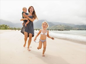 Mother with daughters (6-11 months, 2-3) on beach